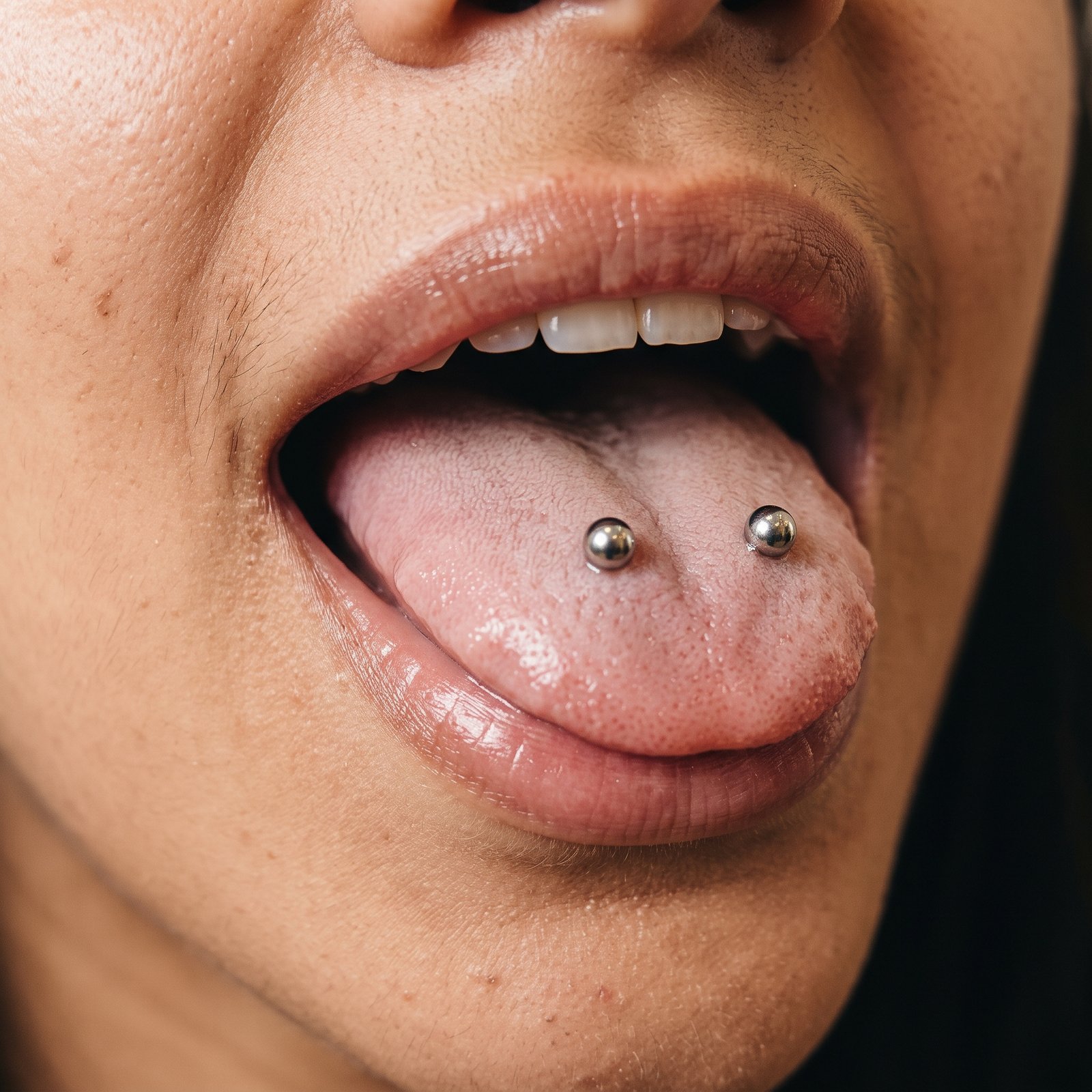 Dois piercings verticais distintos na língua, um de cada lado, na configuração Venom
